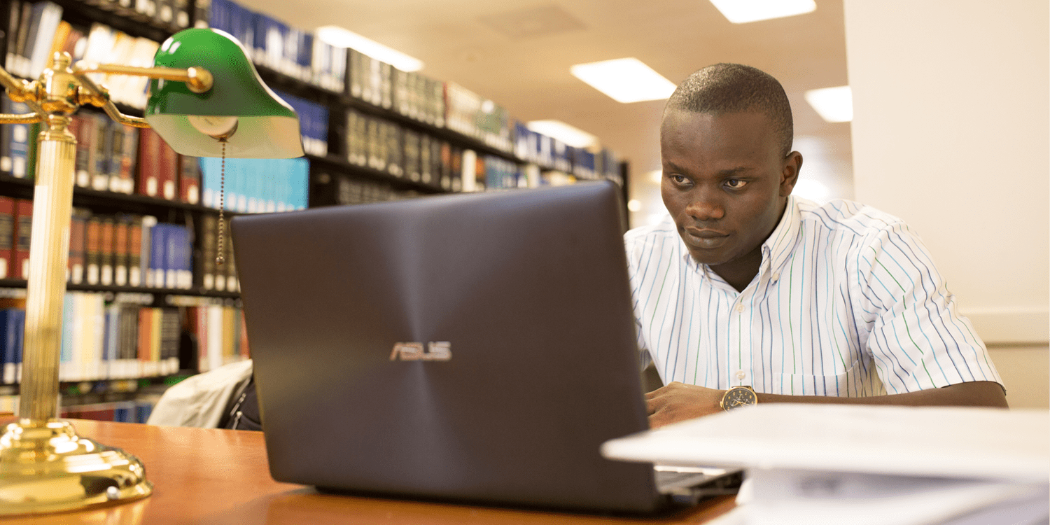 Student Sitting At Desk With Laptop